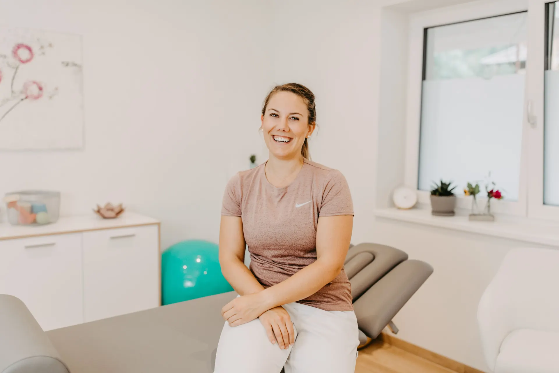Christina Harz lächelt in ihrer hellen Physiotherapie-Praxis in Eben im Pongau