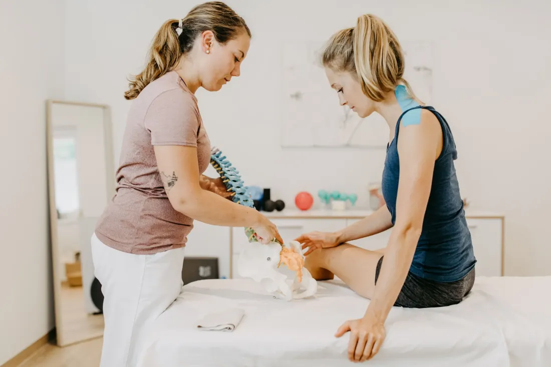 Christina Harz erklärt einer Patientin die Wirbelsäule anhand eines anatomischen Modells
