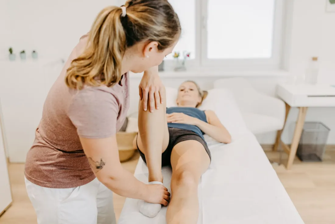 Physiotherapeutische Mobilisation des Beins auf der Behandlungsliege