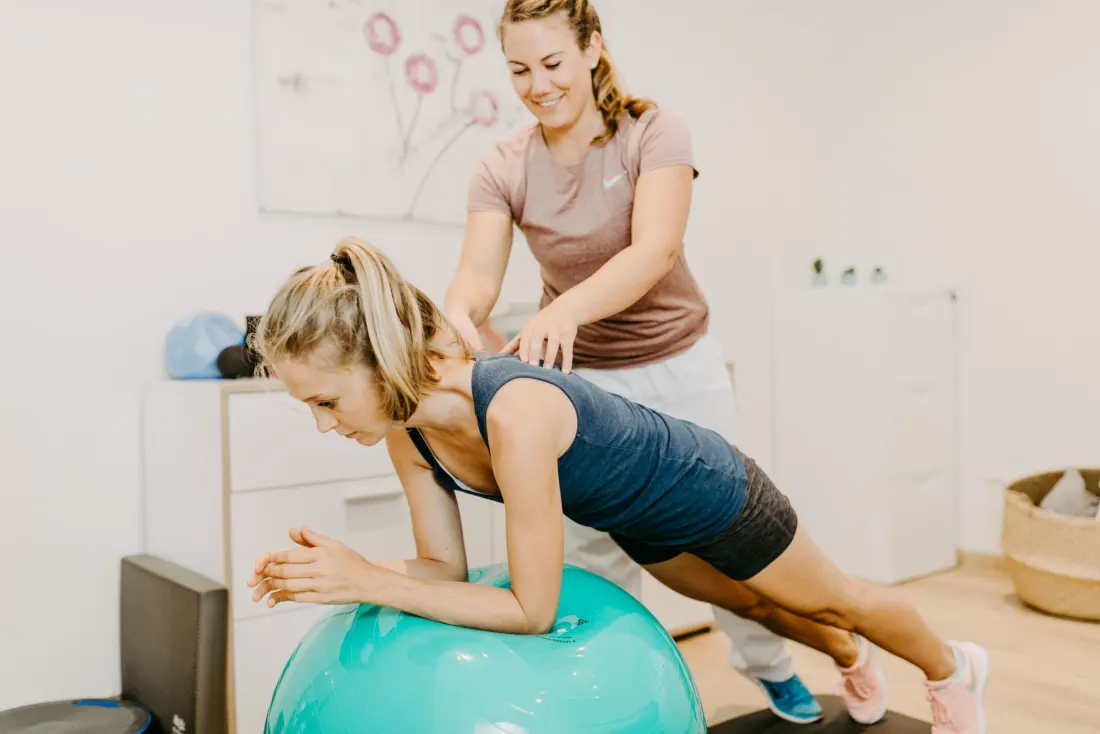 Stabilisationsübung auf dem Gymnastikball während der Sportphysiotherapie